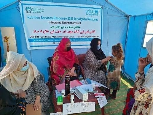 Health workers screening a young girl at a nutrition centre in a tent